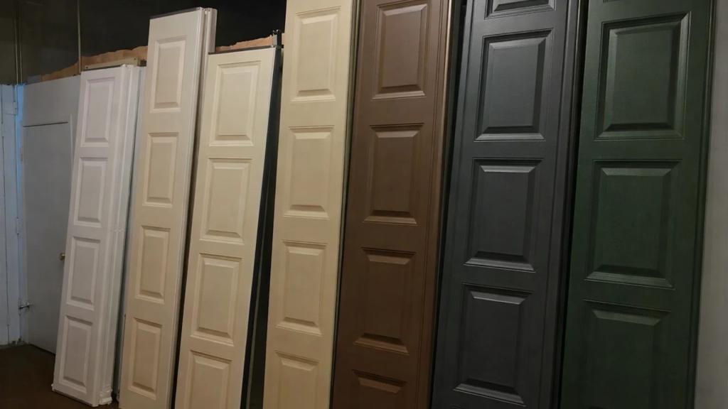Row of six garage door panels in various colors featuring white, beige, brown, and green